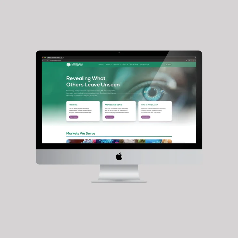 A desktop computer displays a website with a teal banner, the text “Revealing What Others Leave Unseen,” and three information cards about products, markets, and the company, featuring a close-up image of an eye in the background.