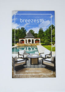 Cover of a Breezesta 2020 Furniture Collection catalog, perfect for advertising or marketing, featuring a luxurious outdoor patio set by a pool, with a pavilion and trees in the background under a blue sky.