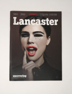 A magazine cover titled Inside Lancaster featuring a woman with bold makeup, red lipstick, and dramatic eyeliner, posing with her mouth open and finger near her lips. This issue highlights uncovering influencers in the world of marketing.