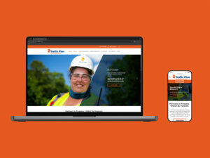 A laptop and a smartphone display the Traffic Plan website homepage, featuring a smiling construction worker in safety gear and a hard hat, highlighting the company's marketing expertise against an orange background.